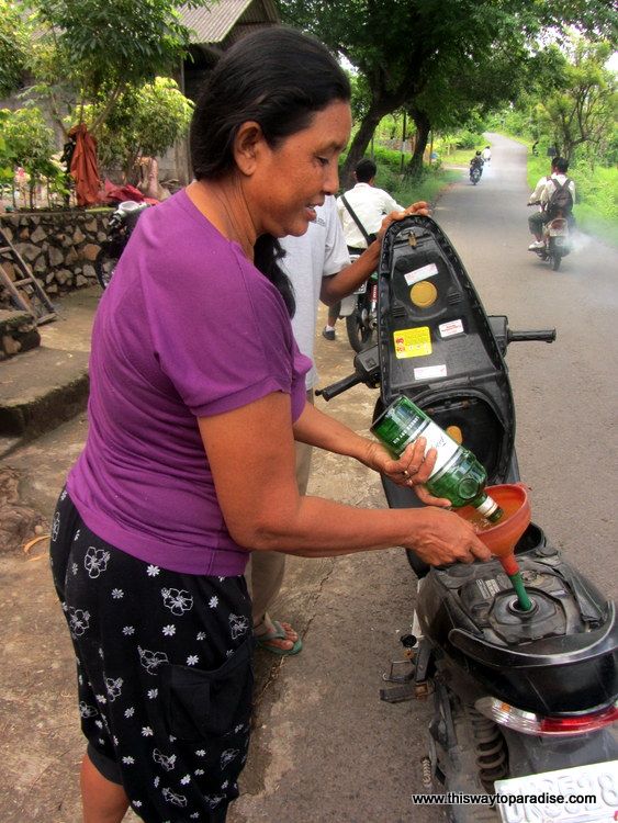 Woman filling motorcycle with petrol in Bali