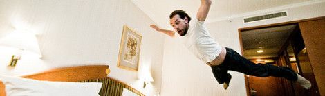 man jumping on bed in hotel accommodation