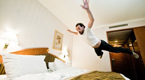man jumping on bed in hotel accommodation