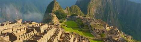 Aerial view of Machu Picchu’s ancient Inca citadel nestled in the Andes mountains with mist and lush landscape.