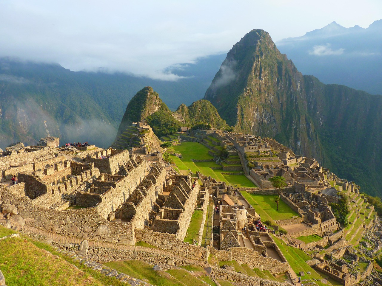 Aerial view of Machu Picchu’s ancient Inca citadel nestled in the Andes mountains with mist and lush landscape.
